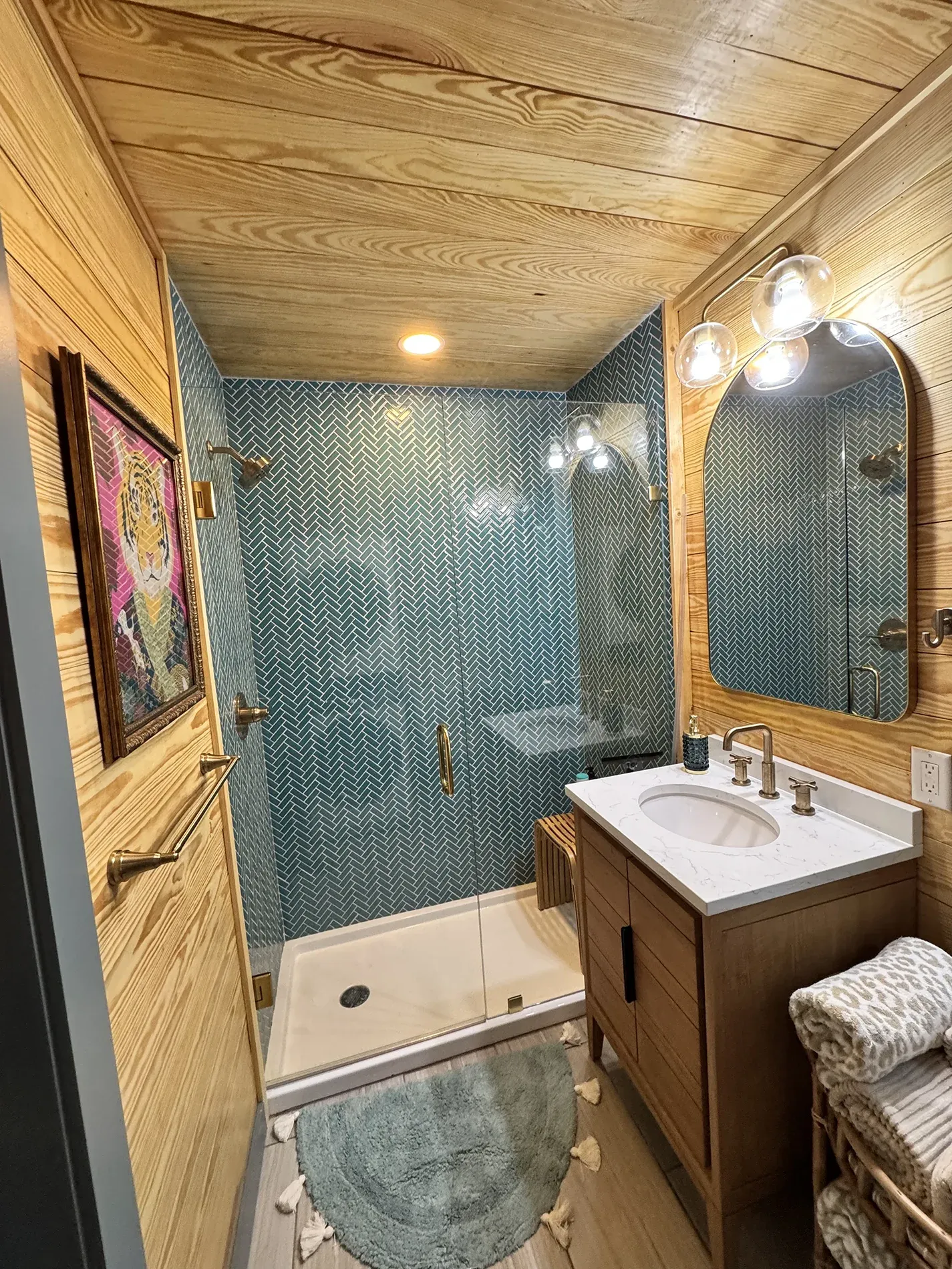 Walk-in shower in teal herringbone tile with brass fixtures