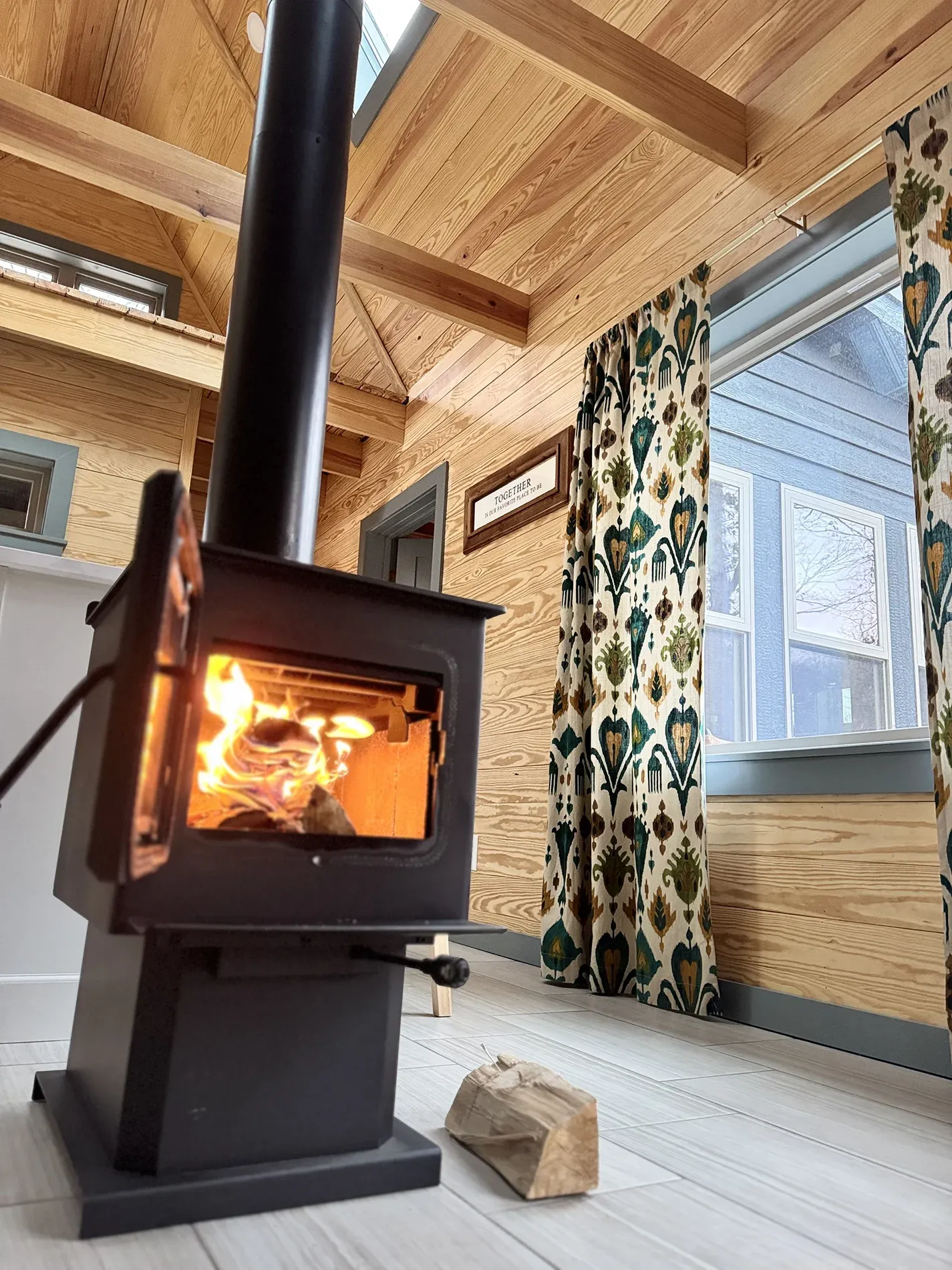 Cabin living area warmed by a cast-iron wood stove, pine walls glowing